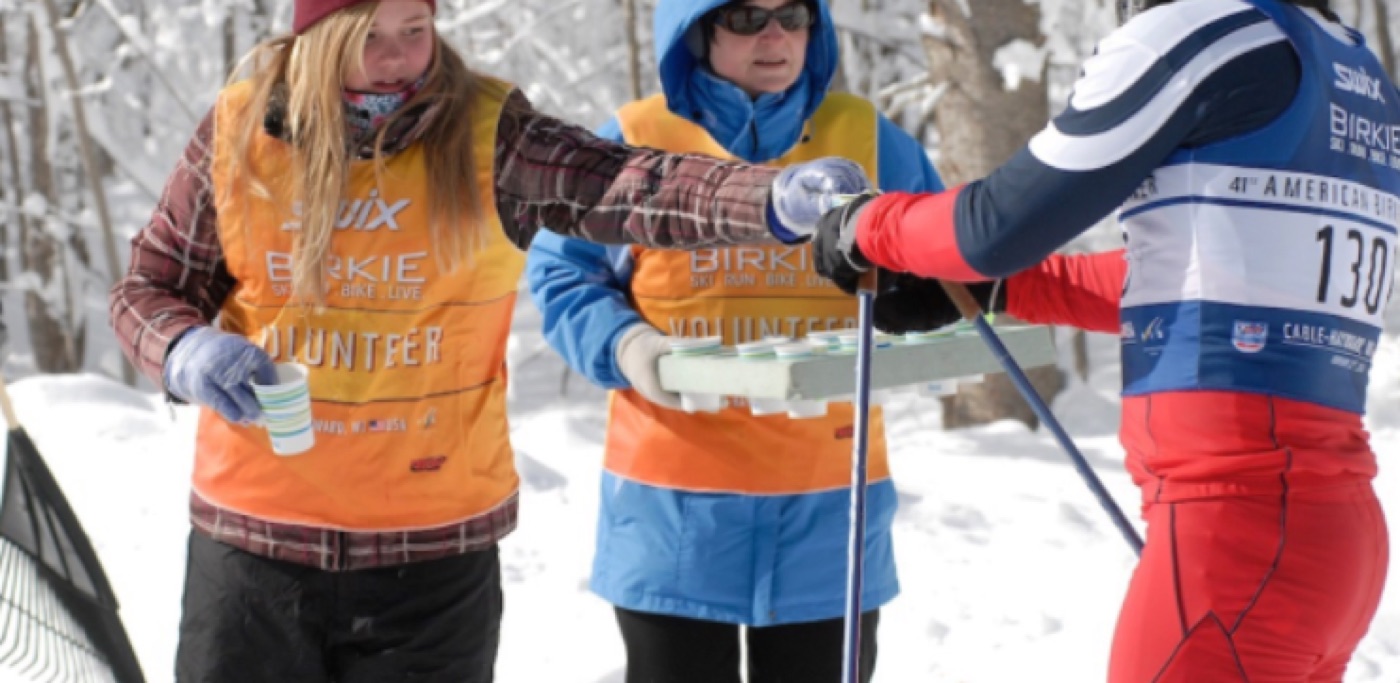 Volunteers in orange volunteer bibs at a Birkie feed station