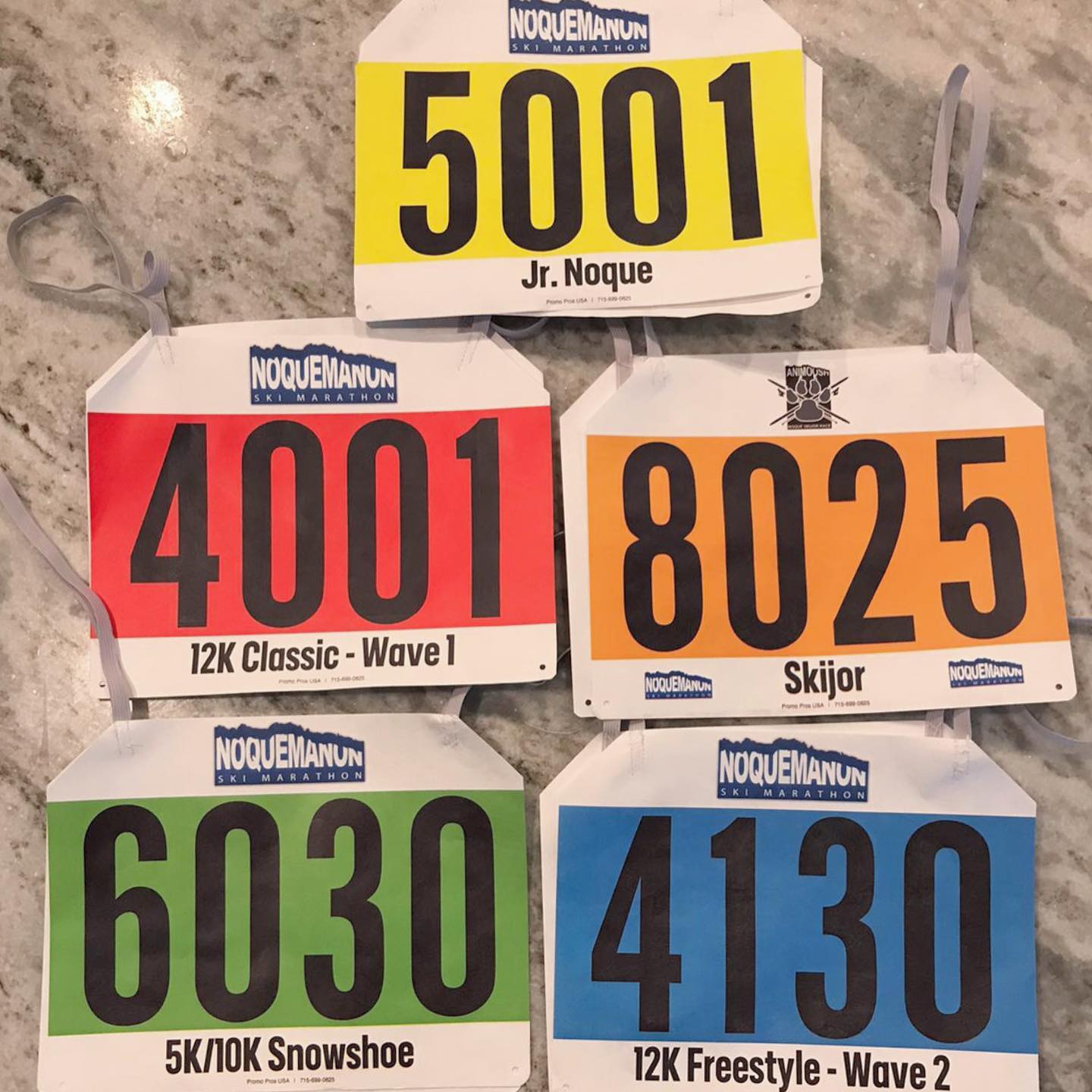 Five color-coded division bib sets for the Noquemanon Ski Marathon
