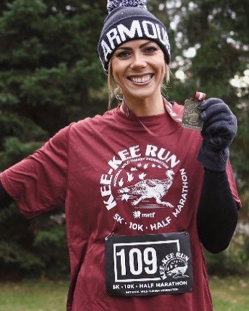 KEE-KEE Run finisher smiling at the finish holding her medal